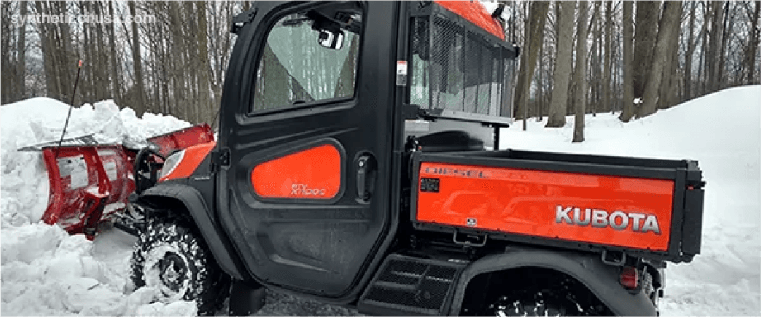 Orange Kubota RTV utility vehicle with enclosed cab in snow