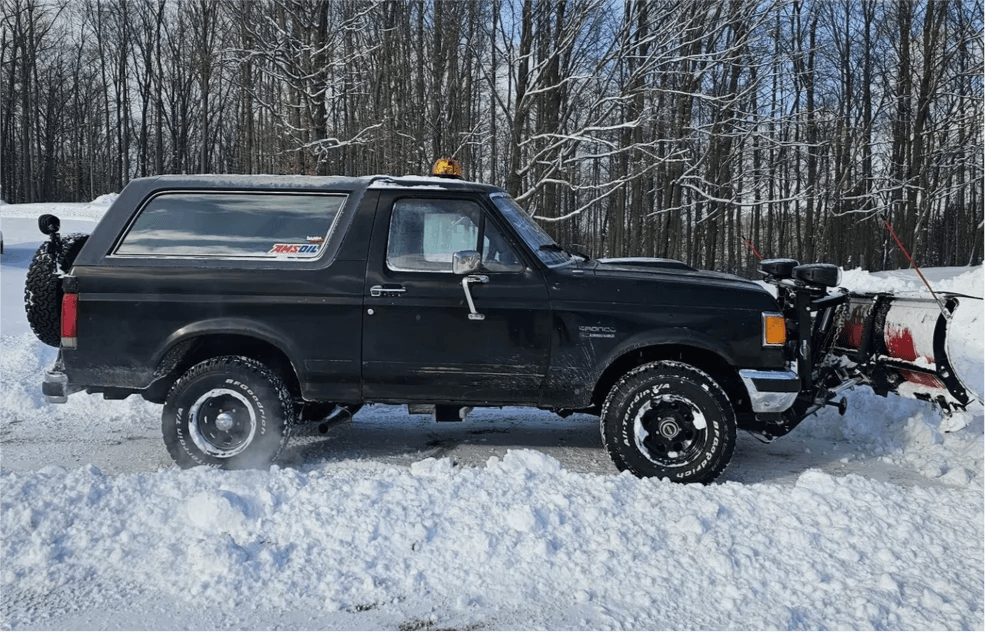 Black Ford Bronco with snow plow in winter