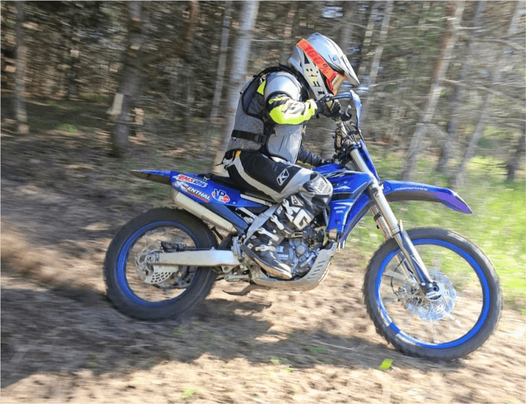 Dave Mann riding a blue Yamaha dirt bike through the woods