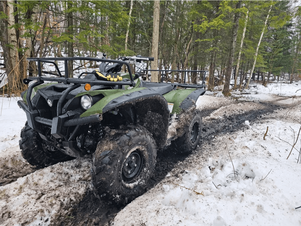 Green Yamaha Grizzly ATV navigating a snowy trail