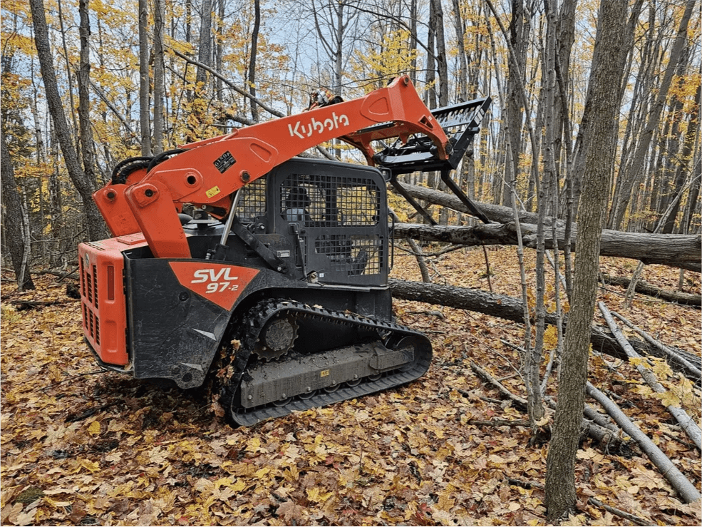 Kubota SVL track loader with raised arm in autumn woods
